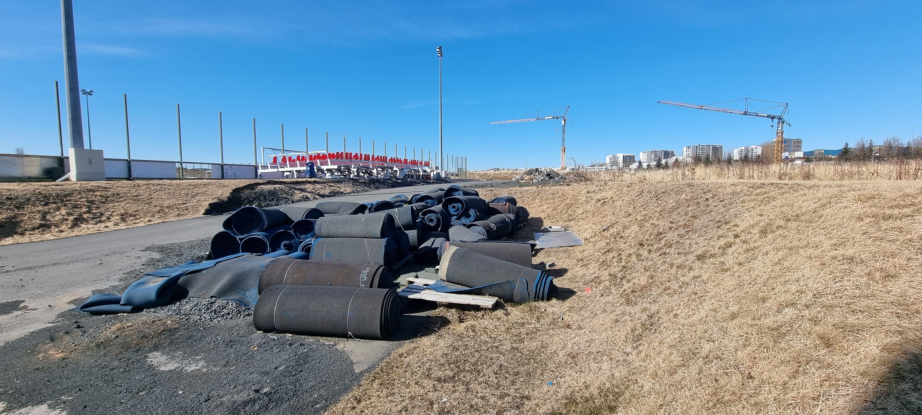 Tartanrúllur, skildar eftir á göngustíg við ÍR, með krönum í bakgrunni.